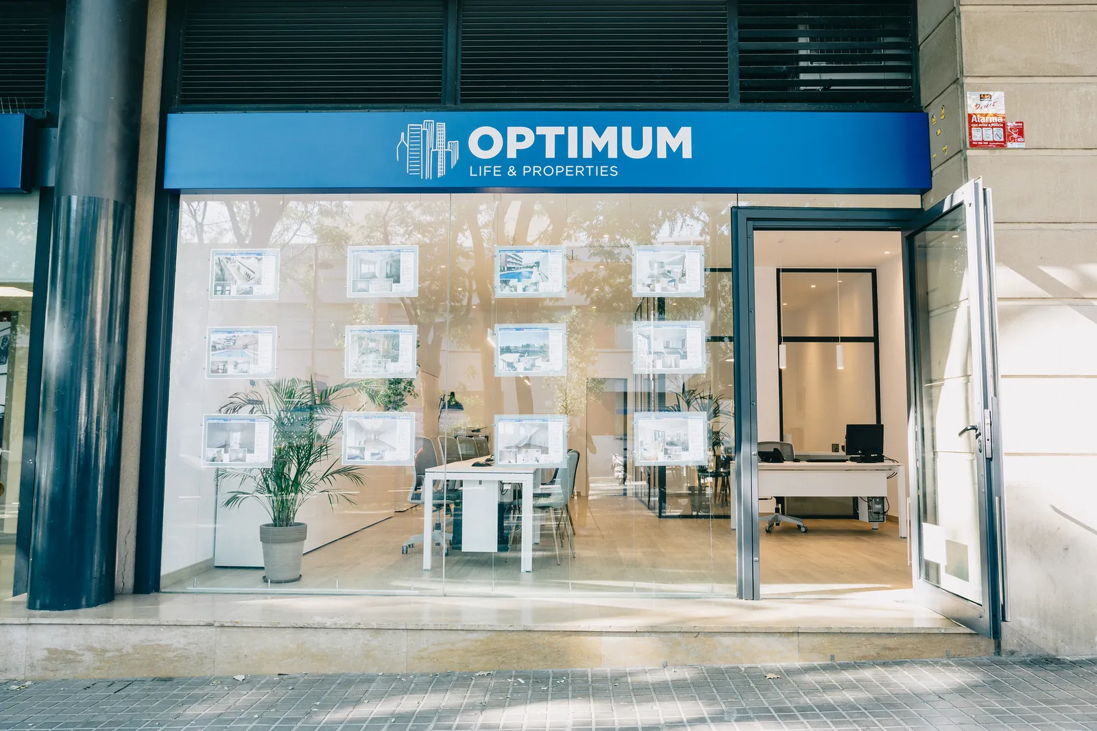 Escaparate de la oficina de Optimum en la calle Comtes de Bell-lloc, en Les Corts, con la puerta abierta